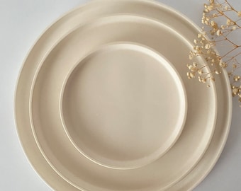 May include: Three white ceramic plates of different sizes stacked on top of each other.