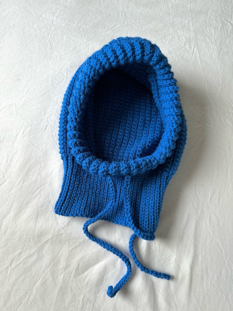 Puede incluir: Una bufanda de punto azul con capucha y cord&oacute;n.
