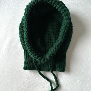 Puede incluir: Una bufanda de punto con capucha de color verde oscuro con cord&oacute;n.