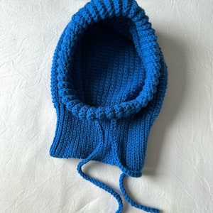Puede incluir: Una bufanda de punto azul con capucha y cord&oacute;n de ajuste.