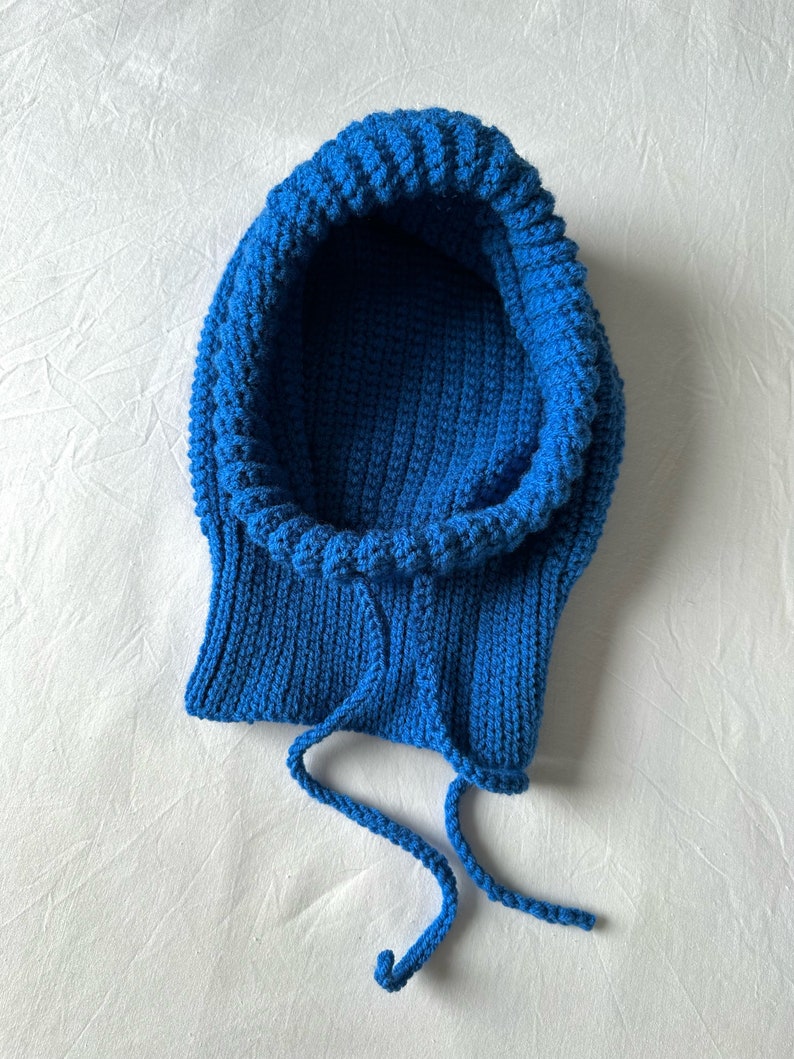 Puede incluir: Una bufanda de punto azul con capucha y cord&oacute;n de ajuste.