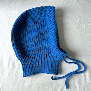 Puede incluir: Un gorro azul de punto con capucha y una larga cuerda de corbata.