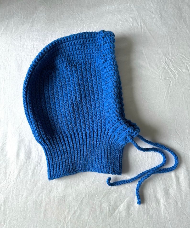 Puede incluir: Un gorro azul de punto con capucha y una larga cuerda de corbata.