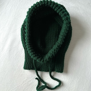 Puede incluir: Un gorro de punto verde oscuro con capucha y cord&oacute;n.