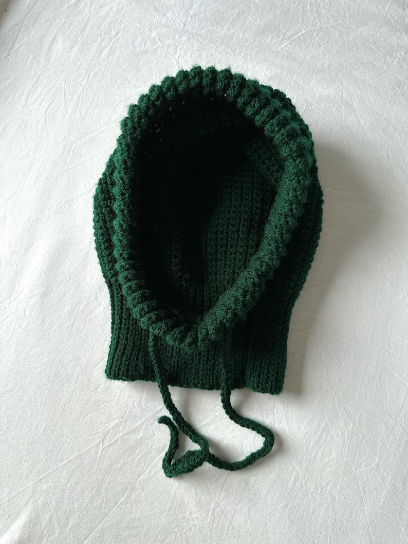Puede incluir: Un gorro de punto verde oscuro con capucha y cord&oacute;n.