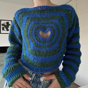 May include: A blue and green striped crocheted jumper with a heart-shaped cutout in the front.