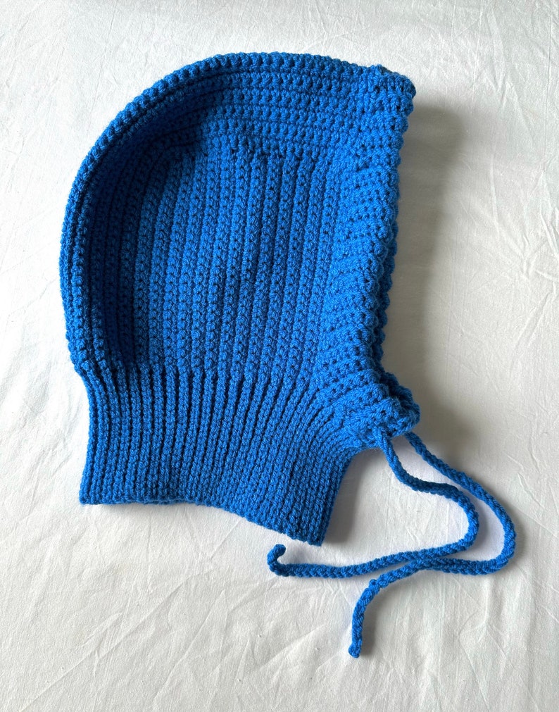 Puede incluir: Un gorro de punto azul con capucha y una larga corbata. El gorro est&aacute; hecho con un patr&oacute;n de punto sencillo y tiene un ajuste holgado.