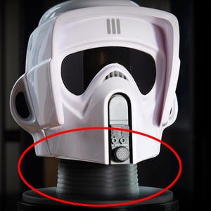 Puede incluir: Réplica de casco de soldado explorador de Star Wars de plástico blanco. El casco presenta una visera, detalles de ventilación y una zona de barboquejo. Está montado sobre una base cilíndrica negra con textura acanalada, para exhibición.