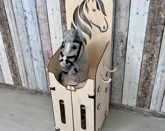 May include: Wooden toy horse stable with a gray plush horse inside. The stable has a cutout of a horse's head on the front and a small door with two shelves.