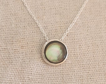 May include: A silver chain necklace with a round pendant featuring a green and black abalone shell.