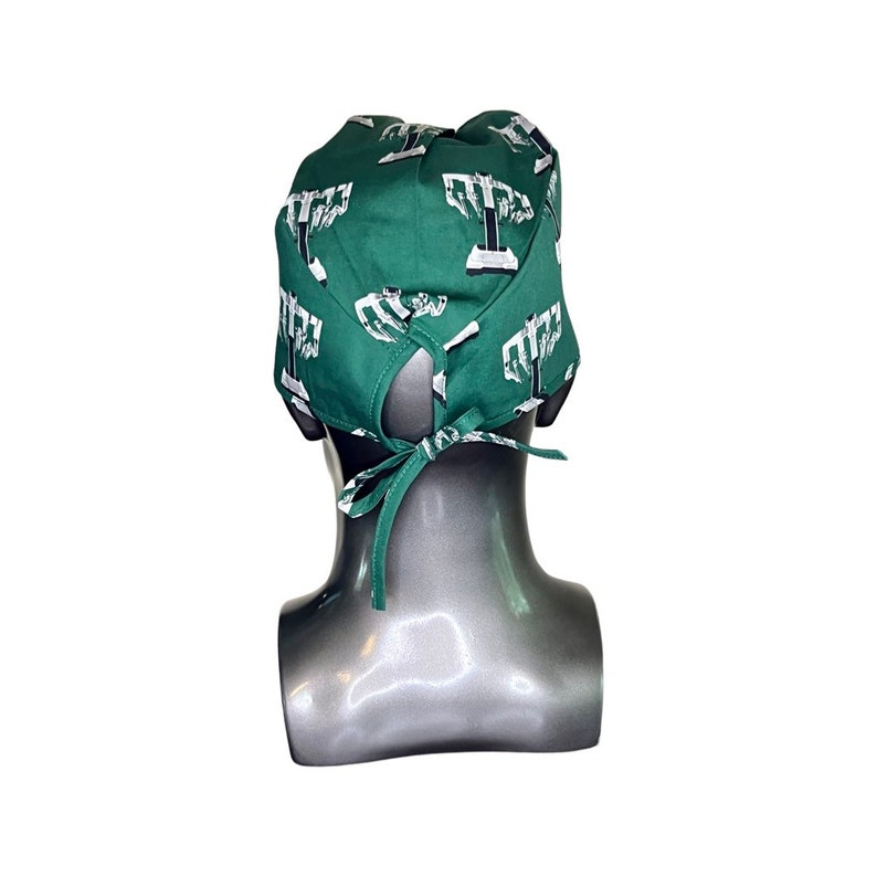 Pode incluir: Um gorro de cirurgia verde com um padr&atilde;o de menor&aacute; branco. O gorro tem um la&ccedil;o na parte de tr&aacute;s.