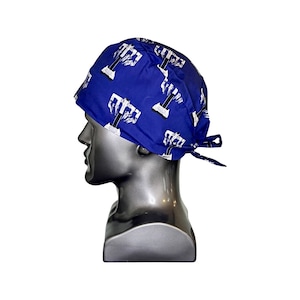 Pode incluir: Chap&eacute;u de esfrega&ccedil;o cir&uacute;rgico azul com um padr&atilde;o de menor&aacute; branco. O chap&eacute;u tem um la&ccedil;o na parte de tr&aacute;s.