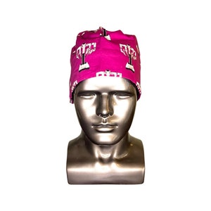 Pode incluir: Um gorro cir&uacute;rgico rosa com um padr&atilde;o de menor&aacute; branco.