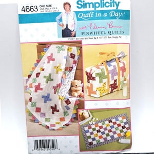 May include: Simplicity Quilt in a Day pattern featuring pinwheel quilts. The image shows a quilt, diaper bag, and baby changing pad. The quilt is white with colorful pinwheel blocks and a scalloped edge. The diaper bag and changing pad also feature pinwheel designs.