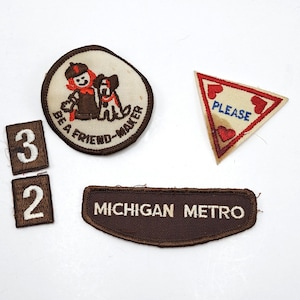 May include: A selection of vintage embroidered patches. Includes a round patch with a cartoon figure and dog, a triangle patch with the word "PLEASE", two number patches, and a brown patch with "MICHIGAN METRO" text.