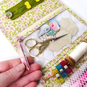 May include: A floral fabric sewing kit with a zippered pouch, clear plastic pockets, and a mesh compartment. The kit contains sewing needles, scissors, thread, and other sewing supplies.
