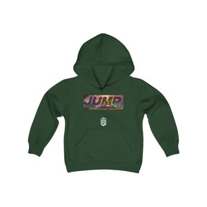 Puede incluir: Una sudadera con capucha verde oscuro con la palabra "JUMP" impresa en colores arcoíris en la parte delantera. La palabra está sobre un fondo de puesta de sol con nubes. Un pequeño logotipo está impreso debajo de la palabra.