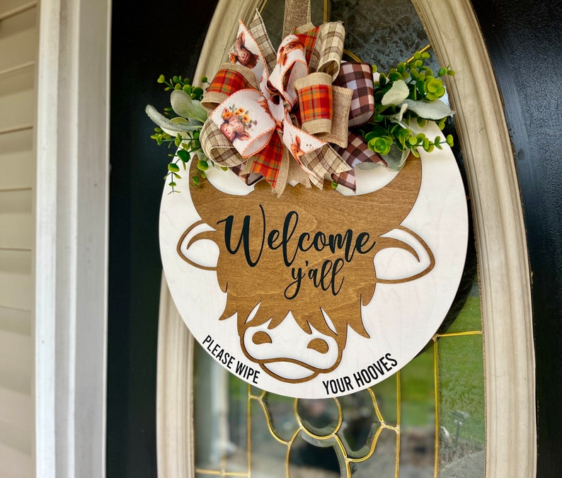 All season door hanger laser cut image long hair highland cow. Humorous "Please wipe your hooves"