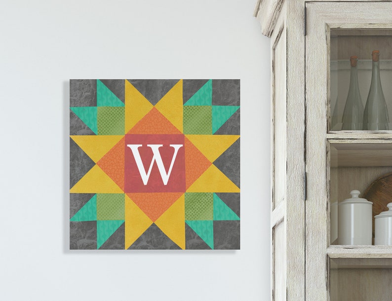 May include: A colorful quilt block with a star design in shades of yellow, orange, red, green, and gray. The center of the block features a white letter "W" on a red background.