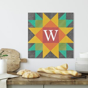 May include: A colorful quilt block with a star design in shades of yellow, orange, red, green, and blue. The center of the block features the letter "W" in white.