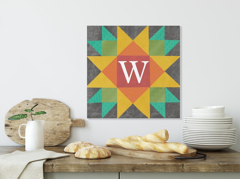 May include: A colorful quilt block with a star design in shades of yellow, orange, red, green, and blue. The center of the block features the letter "W" in white.