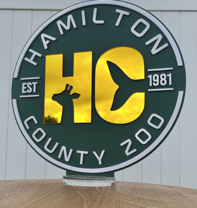 a circular sign with the text "HAMILTON COUNTY ZOO" and a silhouette of a giraffe.
