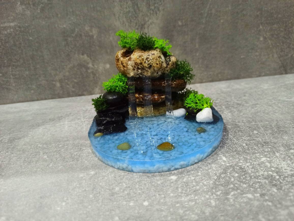First attempt at a Faux Waterfall Terrarium. Water is glow in the dark!  Products used: Fishbowl, polymer clay, uv resin, epoxy resin, sand, fake  moss, Perfect Cast plaster, tan paint, hot glue. 