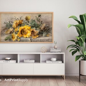 May include: A framed watercolor print featuring a still life of sunflowers in shades of yellow and brown. The artwork is displayed above a white cabinet with decorative items and a potted plant. The print is labeled "ArtPrintSupply" in the bottom left corner.