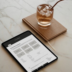 Puede incluir: Una tableta mostrando un tablero de planificaci&oacute;n personal con secciones para objetivos, proyectos, tareas, calendario, notas y organizaci&oacute;n. La tableta est&aacute; sobre una superficie de m&aacute;rmol blanco con un vaso de t&eacute; helado y una libreta marr&oacute;n.