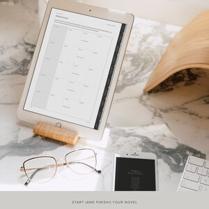 May include: A white tablet computer displaying a printable novel writing planner with the title "Allotment Tracker". The tablet is propped up on a wooden stand. A pair of gold-rimmed glasses and a white smartphone with the text "Writing Your Novel" are also visible on a marble surface.