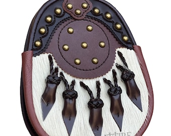 May include: A brown leather sporran with a white fur flap and five brown leather tassels. The sporran has a circular, brown leather flap with gold studs and a decorative border.