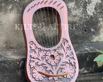 May include: A wooden lyre with a floral design carved into the body. The lyre has 10 strings and is made of a dark wood.