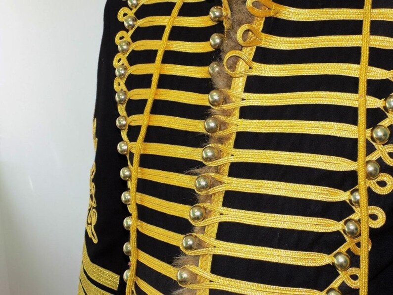 May include: A black jacket with gold trim and silver buttons. The jacket has a military style with a row of buttons down the front and a decorative braid.