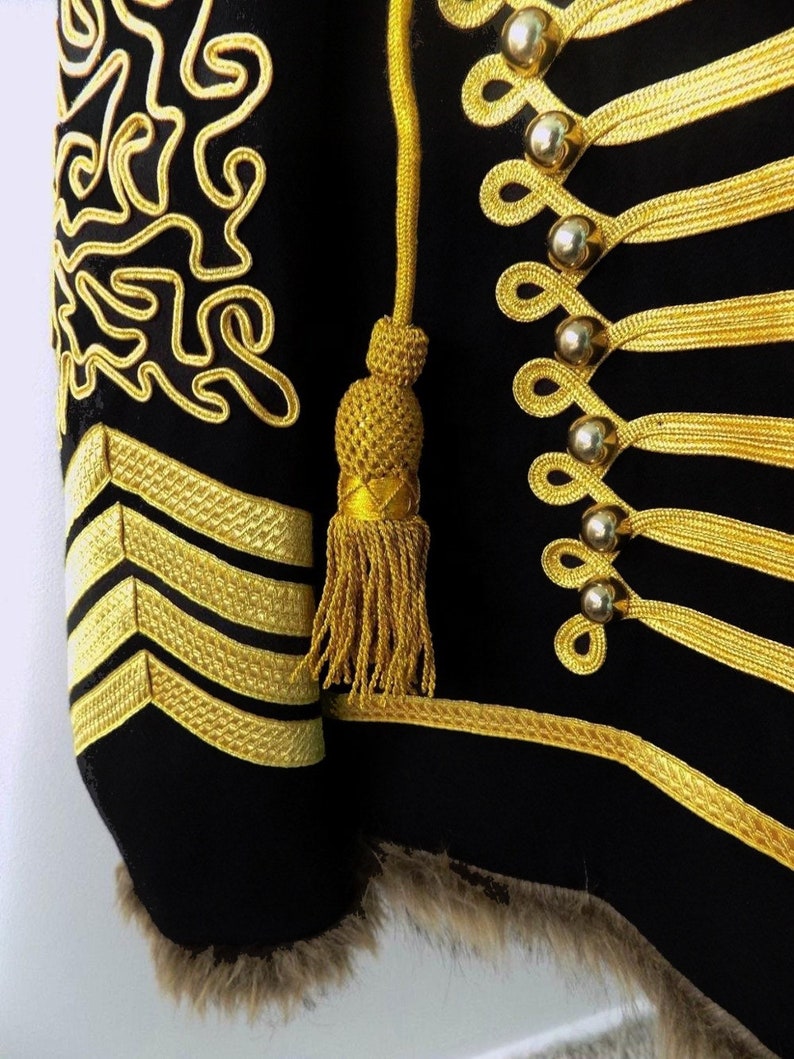 May include: A black jacket with gold trim and buttons. The jacket has a fur collar and a gold tassel on the sleeve.