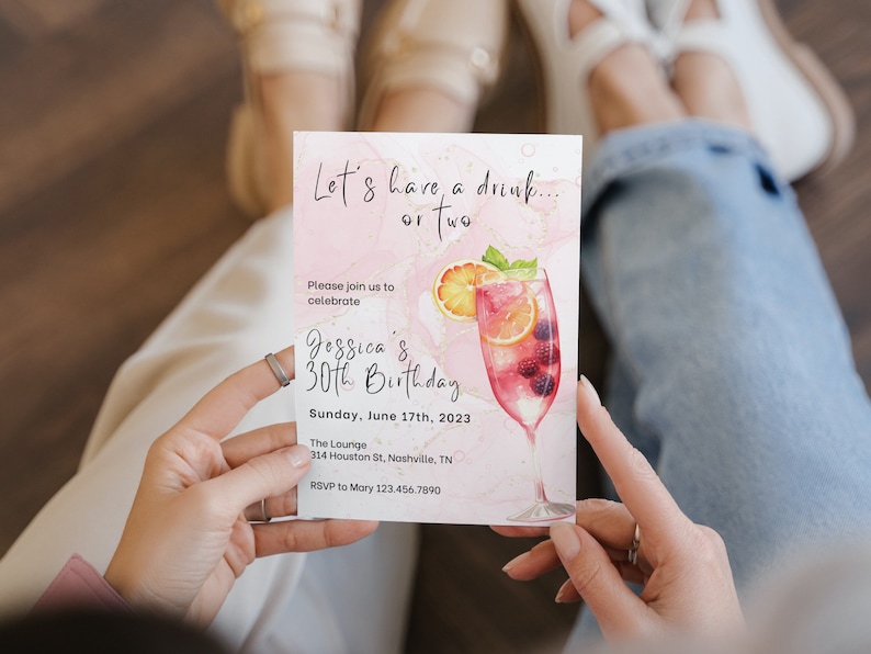 May include: Pink and gold birthday invitation with a watercolor illustration of a cocktail glass filled with fruit and berries. The text reads "Let's have a drink... or two. Please join us to celebrate Jessica's 30th Birthday. Sunday, June 17th, 2023. The Lounge, 314 Houston St, Nashville, TN. RSVP to Mary 123.456.7890"
