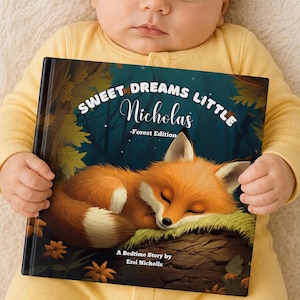 以下が含まれることがあります： 「Sweet Dreams Little Nicholas -Forest Edition-」というタイトルのハードカバーの絵本。苔むした丸太の上で眠るオレンジ色のキツネのイラストが描かれています。表紙には「A Bedtime Story by Ersi Nicholls」というテキストが記載されています。