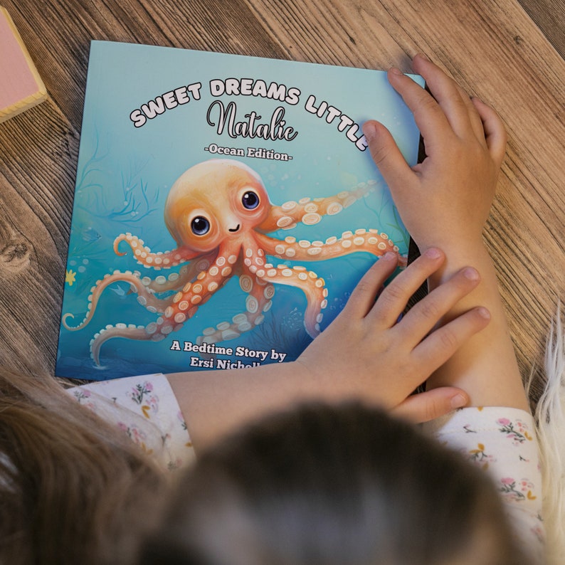 May include: A blue and orange children's book titled "Sweet Dreams Little Natalie - Ocean Edition -" with an illustration of a smiling octopus on the cover. The book is a bedtime story by Ersi Nicholl.