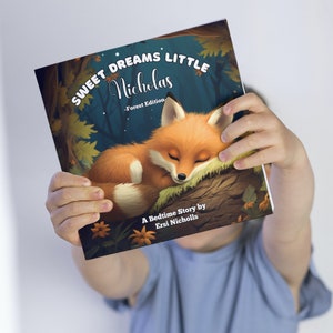 Może przedstawiać: Prezentowana jest książka dla dzieci zatytułowana "Sweet Dreams Little Nicholas - Forest Edition". Okładka przedstawia ilustrację śpiącego pomarańczowego lisa na gałęzi drzewa, z ciemnoniebieskim tłem lasu. Widoczne jest r&oacute;wnież nazwisko autora.