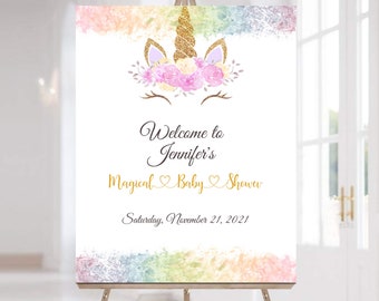May include: A white welcome sign with a rainbow watercolor background. A gold glitter unicorn head with pink flowers is at the top. The text reads "Welcome to Jennifer's Magical Baby Shower Saturday, November 21, 2021".