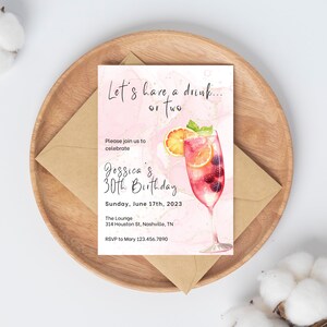 May include: Pink and gold birthday invitation with a watercolor illustration of a cocktail glass with fruit and berries. The text reads "Let's have a drink... or two. Please join us to celebrate Jessica's 30th Birthday. Sunday, June 17th, 2023. The Lounge, 314 Houston St, Nashville, TN. RSVP to Mary 123.456.7890"