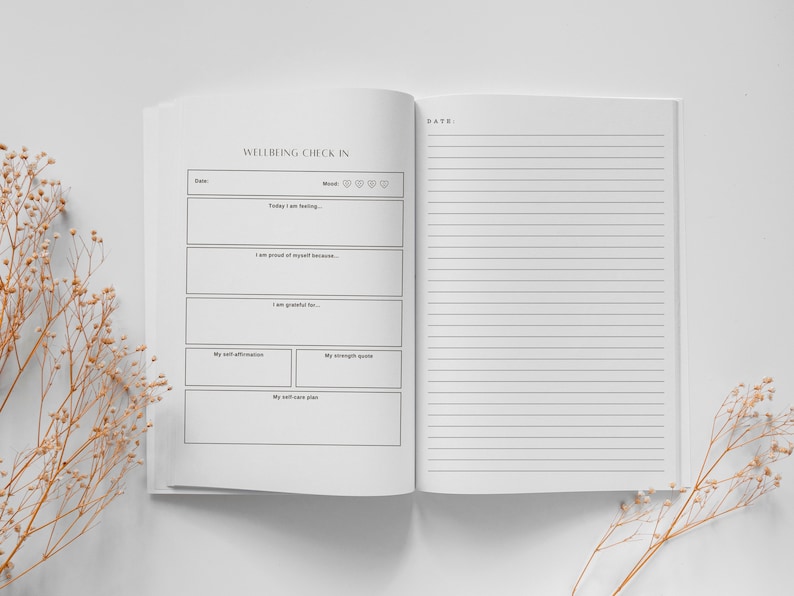 May include: A white journal with the title "Wellbeing Check In" and a section for daily self-reflection. The journal has sections for mood, self-affirmations, strength quotes, and a self-care plan. The right page is blank with lined paper.