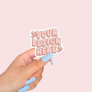 Könnte beinhalten: Ein Aufkleber mit dem Text "YOUR DESIGN HERE" in einer Retro-Schriftart, gehalten von einer Hand mit hellblauen Nägeln. Der Aufkleber hat einen weißen Rand und ein Pfirsich- und Braunschema mit Sternakzenten.