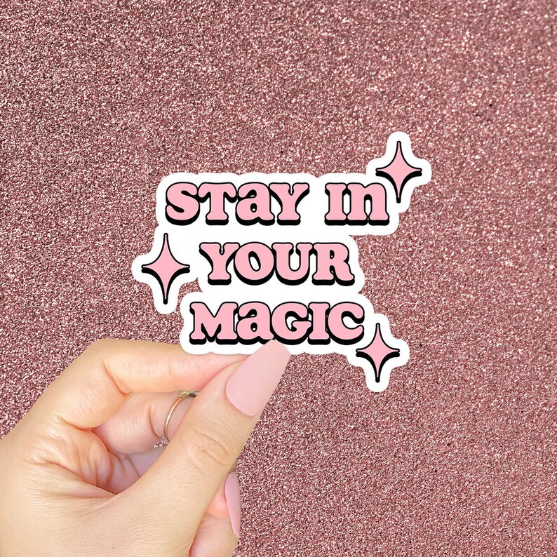 May include: Pink and white sticker with the text "Stay in your magic" and four small pink stars.