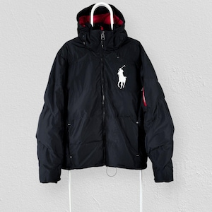 Puede incluir: Una chaqueta acolchada negra con capucha y forro interior rojo, cremallera frontal completa y un logotipo blanco bordado de un caballo y jinete de Polo Ralph Lauren en el pecho izquierdo. La chaqueta tiene mangas largas y un dobladillo ajustable.