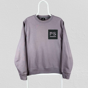 May include: A mauve long-sleeve crewneck sweatshirt featuring a black square graphic on the left chest. Inside the black square, the letters PS are printed in white, with a horizontal line underneath the letters. The sweatshirt has ribbed cuffs.