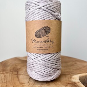 May include: A spool of light gray cotton cord for macrame projects. The label reads "Macram Akkiz L'univers du macrame Corde Macrame 100% Coton Qualite premium".