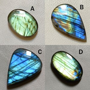 Peut inclure: Quatre cabochons de labradorite en forme de pierres pr&eacute;cieuses de diff&eacute;rentes formes et tailles. Les pierres ont un &eacute;clat iridescent bleu, vert et or.