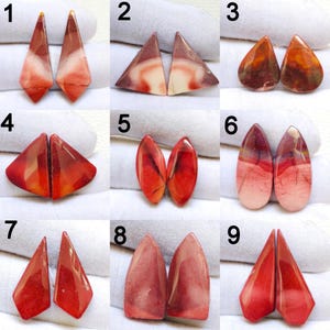 May include: A collection of nine pairs of polished gemstone cabochons in various shapes and colors. The gemstones range from triangular to teardrop and oval shapes, with colors including red, orange, brown, and cream. Each pair is displayed on a white surface.