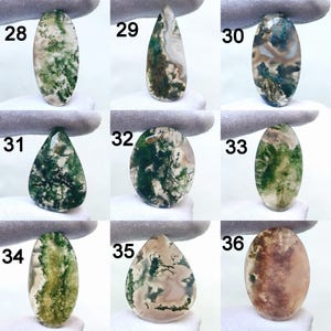 May include: Nine polished moss agate gemstones in various shapes, including oval and teardrop. The stones display green, white, and brown patterns, with each stone labeled with a number from 28 to 36.