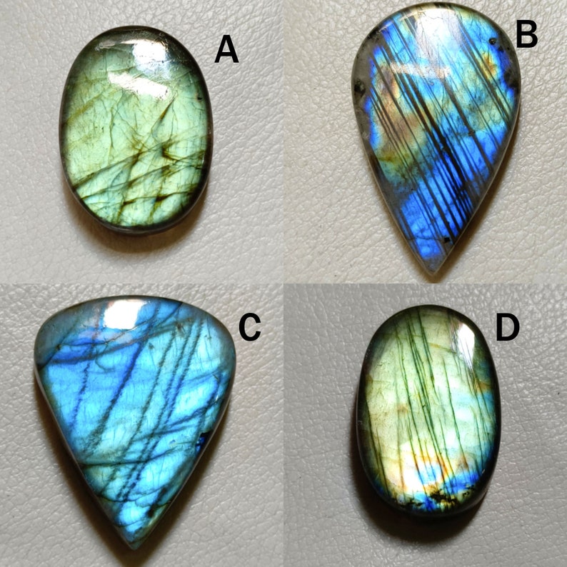 Peut inclure: Quatre cabochons de labradorite en forme de pierres pr&eacute;cieuses de diff&eacute;rentes formes et tailles. Les pierres sont iris&eacute;es avec des nuances de vert, de bleu et d'or.